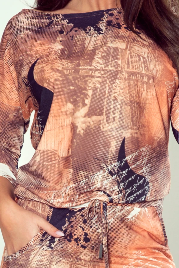 Modelka prezentuje sukienkę z elastycznego materiału w odcieniach brązu z artystycznym nadrukiem i dekoltem, marki Numoco – produkt polski.