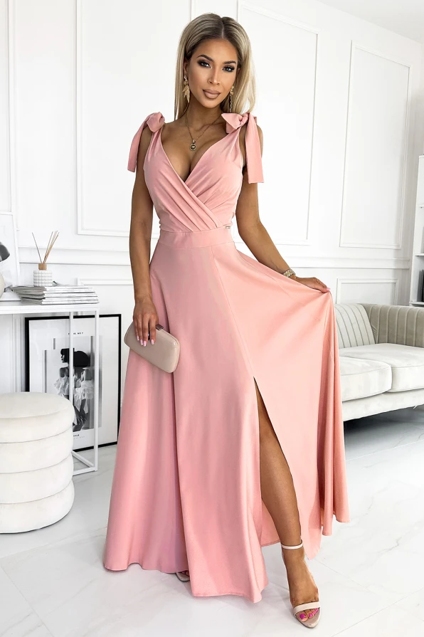 Elegantiška ilga suknelė su gilia iškirpte ir petnešėlėmis, kurios surišamos kaspinėliais. Suknelė turi aukštą skeltuką, suteikiantį elegancijos ir moteriškumo.