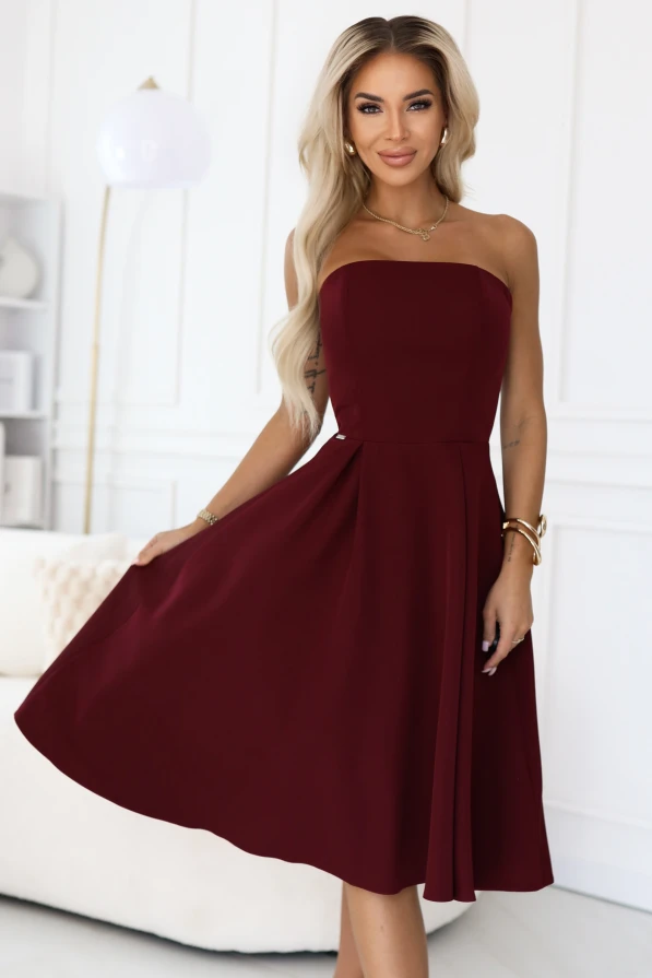 Modelka prezentuje elegancką sukienkę Vivienne midi w kolorze bordowym z rozkloszowanym dołem – stylowa propozycja marki Numoco na wyjątkowe okazje.
