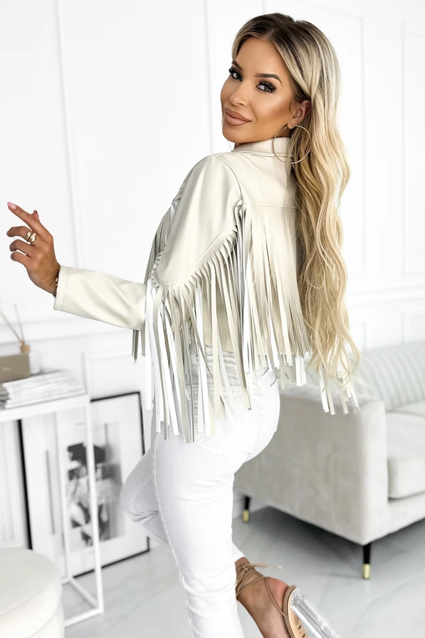 Modelka prezentuje beżową ramoneskę z frędzlami na rękawach i ramionach marki Numoco Basic. Stylizacja w klimacie boho z krótką kurtką idealną na festiwale i miejskie wyjścia.