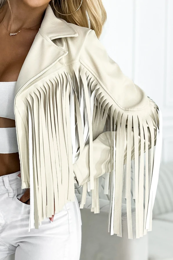 Modelka prezentuje beżową ramoneskę z frędzlami na rękawach i ramionach marki Numoco Basic. Stylizacja w klimacie boho z krótką kurtką idealną na festiwale i miejskie wyjścia.