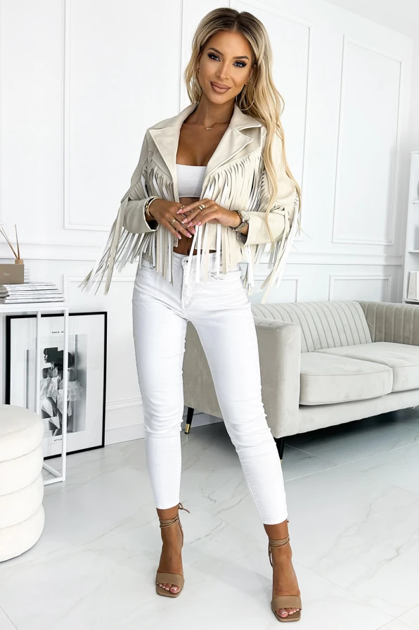 Modelka prezentuje beżową ramoneskę z frędzlami na rękawach i ramionach marki Numoco Basic. Stylizacja w klimacie boho z krótką kurtką idealną na festiwale i miejskie wyjścia.